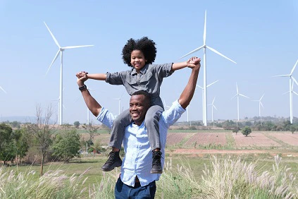 Father Playing With Child With Windfarm In Background