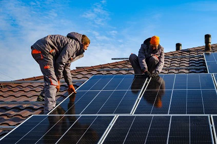Workers Installing Solar Panels On Roof